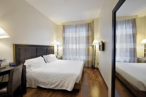 a hotel room with two beds and a desk at Hotel Canada in Milan