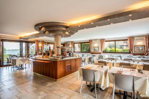 a restaurant with white tables and chairs and windows at Onda Blu Resort in Manerba del Garda