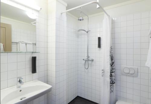 a white bathroom with a shower and a sink at Fosshotel Eastfjords in Fáskrúðsfjörður