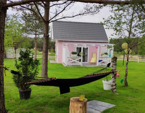 eine Hängematte vor einem rosa Haus in der Unterkunft Bajkowy domek Villa Rosa na Kaszubach in Grzybowo