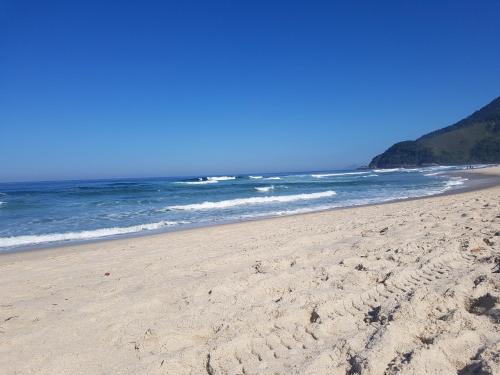 a beach with footprints in the sand and the ocean at Casa Canto do Mar Maresias 2 in Maresias