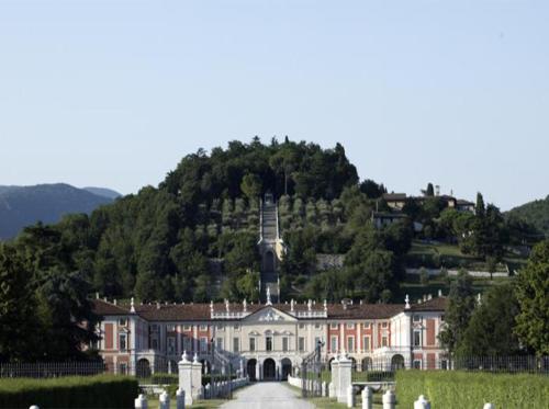 a large building with a hill in the background at Villa Fenaroli Palace Hotel in Rezzato