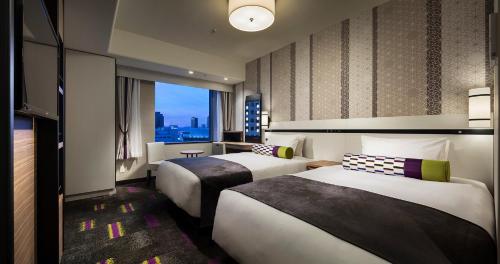 a hotel room with two beds and a window at Hotel Monterey Le Frere Osaka in Osaka