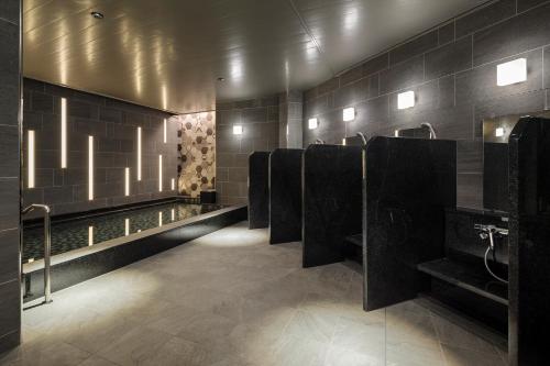 a bathroom with a row of urinals and sinks at Hotel Monterey Le Frere Osaka in Osaka