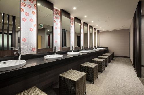 a bathroom with a row of sinks and mirrors at Hotel Monterey Le Frere Osaka in Osaka