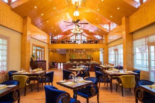 a restaurant with wooden ceilings and tables and chairs at Regenta Inn by Riverside Manali in Manāli