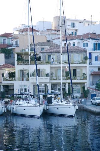 three sailboats are docked in a harbor with buildings at mourayio in Ermioni