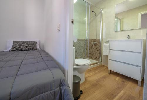 a bedroom with a bed and a shower and a toilet at Apartamentos AR Melrose Place in Lloret de Mar