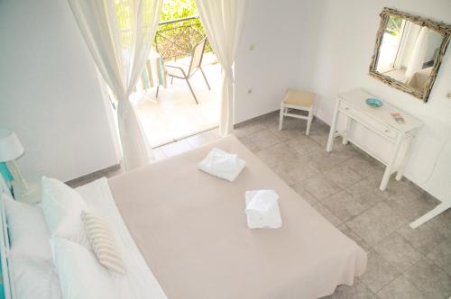 a white room with a bed and a table and a mirror at Heracles Guesthouse in Rovies