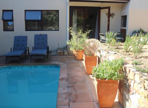 a backyard with a swimming pool and chairs and plants at Malachite Cottage in Kommetjie