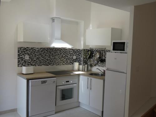 a kitchen with white cabinets and a white refrigerator at Appartement centre historique avec Terrasse au porte de la Camargue in Saint-Gilles