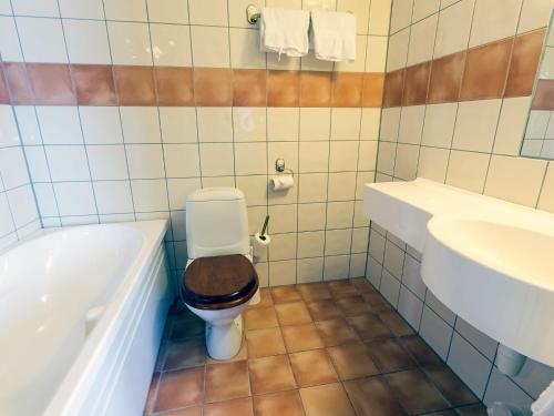 a bathroom with a toilet and a tub and a sink at Strand Hotell Sortland in Sortland