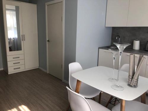 Una cocina blanca con una mesa y sillas blancas. en Alejas Lux Apartment, en Liepāja