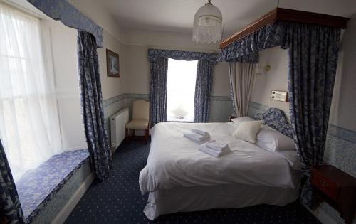 a bedroom with a large bed with blue curtains at Union Hotel in Penzance