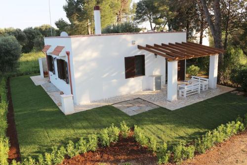 a small white house with a wooden roof at Villa del Sole in Manduria