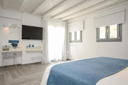 a white bedroom with a blue bed and a desk at Naxos Rock Villas in Stelida