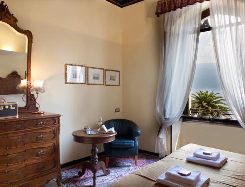a bedroom with a bed and a dresser and a window at Hotel Villa Giulia in Gargnano