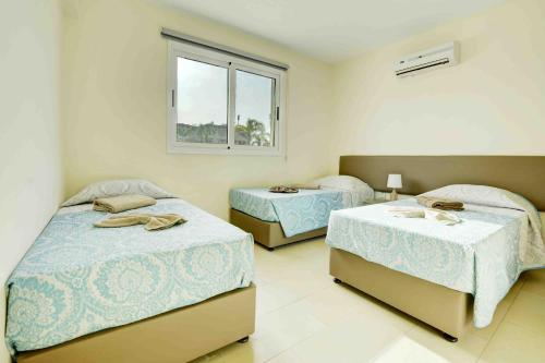 a bedroom with two beds and a window at Nissi Martha Apartment in Ayia Napa
