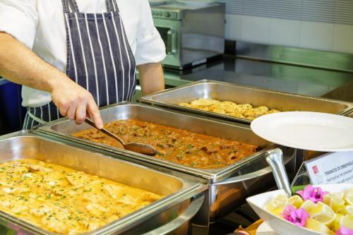 a chef preparing food in trays in a kitchen at Hotel San Pietro in Limone sul Garda