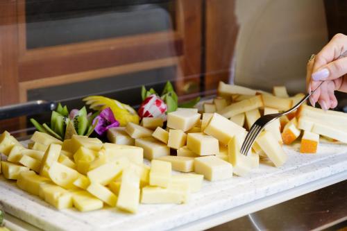 a person cutting cheese on a cutting board with a fork at Hotel San Pietro in Limone sul Garda