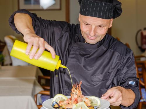 a chef preparing a dish with a plate of food at Hotel San Pietro in Limone sul Garda