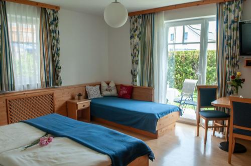 a bedroom with two beds and a desk and a window at Pension Hiesel-Villa Untersbergblick in Anthering