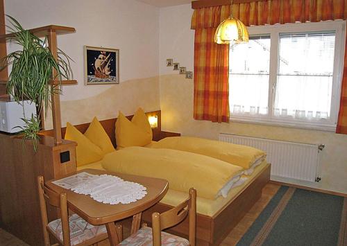 a bedroom with a yellow bed and a table at Gästehaus Steiner in Tröpolach