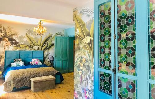 a bedroom with a blue bed and a mural at La Rebière d'Or, B&B et Gîte in Mouleydier
