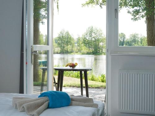 a bedroom with a door open to a view of a lake at Boootshaus - Am Spreeufer in Beeskow