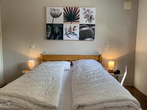 a bed in a bedroom with two lamps and a picture on the wall at Bungalowpark Het Verscholen Dorp in Harderwijk