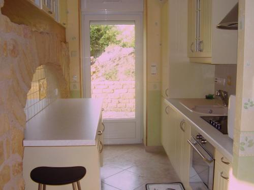 cocina con encimera, fregadero y ventana en La Petite Maison, en Clavy-Warby