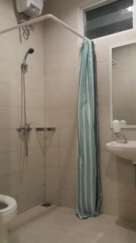 a bathroom with a shower and a toilet and a sink at Redwood Residence in Pangkalpinang