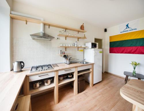a kitchen with a sink, stove, refrigerator, and cabinets at Klaipeda Hostel in Klaipėda