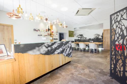 a dining room with a bar with white chairs at Hôtel de France in Montmarault