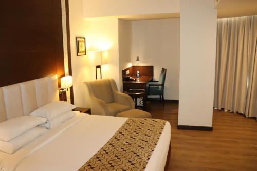 a hotel room with a bed and a chair at Souvenir Jaipur in Jaipur