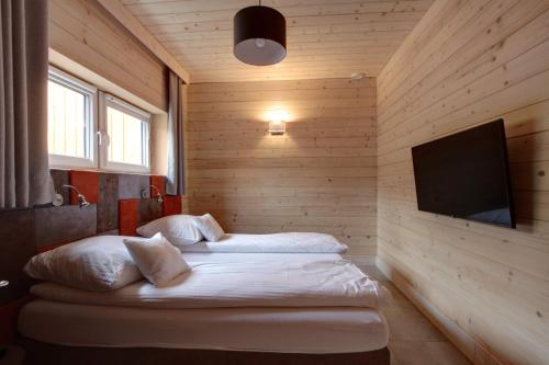 a bedroom with two beds and a flat screen tv at Stranda in Giżycko