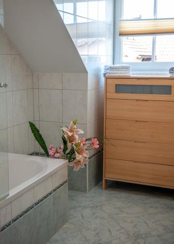 baño con bañera, lavabo y flores en Pension Hiesel-Villa Untersbergblick, en Anthering