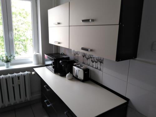 kuchnia z białymi szafkami i blatem z kuchenką mikrofalową w obiekcie Apartament Centrum w Szczecinku