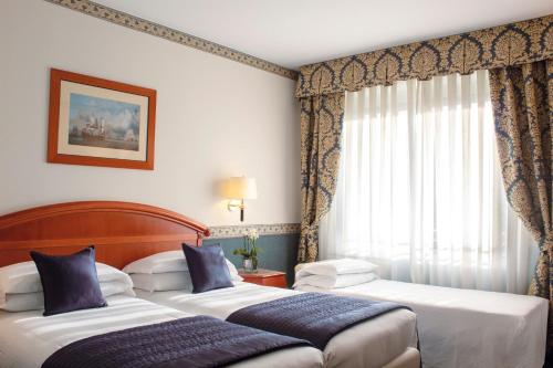 um quarto de hotel com duas camas e uma janela em Starhotels Vespucci em Campi Bisenzio