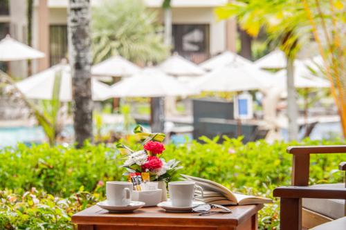 a table with coffee cups and a book and flowers at The Leaf Oceanside by Katathani - SHA Extra Plus in Khao Lak
