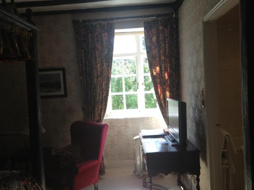 a room with a window and a chair and a television at The Rock Inn in Bovey Tracey