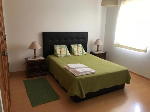 um quarto com uma cama verde com 2 mesas e 2 candeeiros em Nice apartment near Faro's airport em Faro