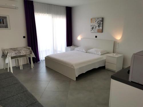 a white bedroom with a bed and a table at Hrvoje in Pag