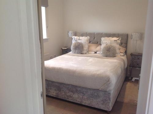 a bedroom with a bed with white sheets and pillows at Oakleigh 1 bed ground floor garden view apartment FREE ONSITE PARKING in Stratford-upon-Avon