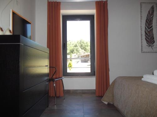 a bedroom with a bed and a television and a window at Quinta dos Carvalhais - Serra da Estrela in Fornos de Algodres