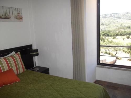 a bedroom with a green bed and a window at Quinta dos Carvalhais - Serra da Estrela in Fornos de Algodres