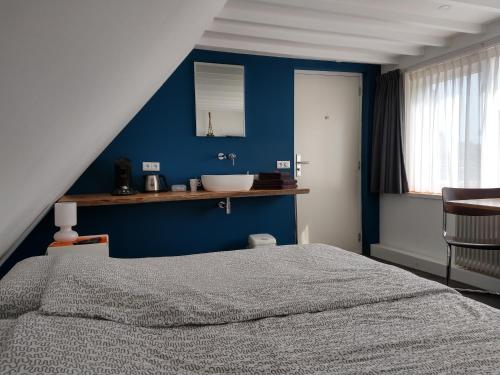 een slaapkamer met een bed en een blauwe muur bij Hoogland aan Zee in Egmond aan Zee