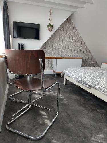 une chaise assise à côté d'un lit dans une pièce dans l'établissement Hoogland aan Zee, à Egmond aan Zee