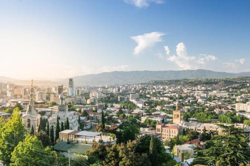 a view of a city with mountains in the background at Hotel Adamo in Tbilisi City