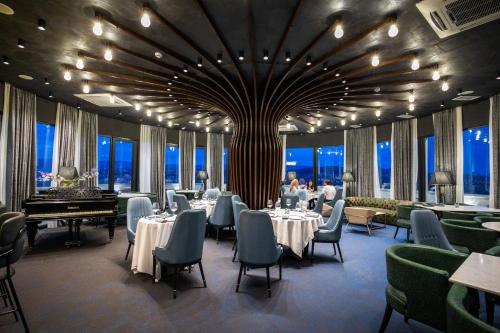 a restaurant with tables and chairs and a grand piano at Hotel Adamo in Tbilisi City